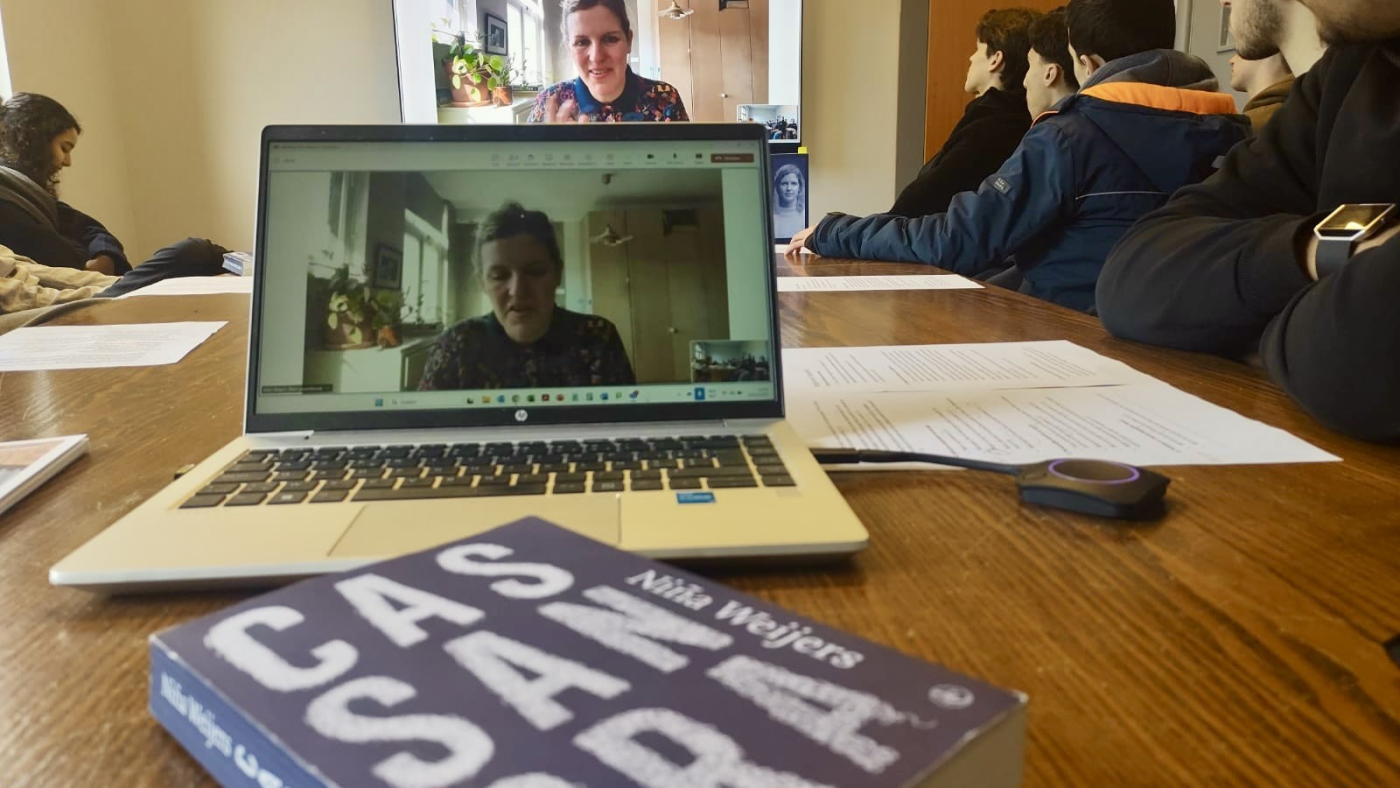 Auteur Niña Weijers geeft lezing via de computer, voor de laptop ligt haar boek Cassandra